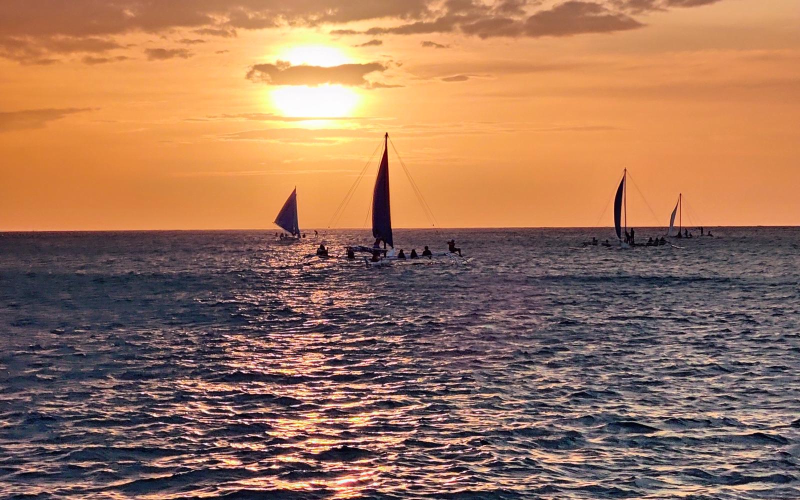 Solnedgang over havet med seilbåter ved Boracay i Filippinene