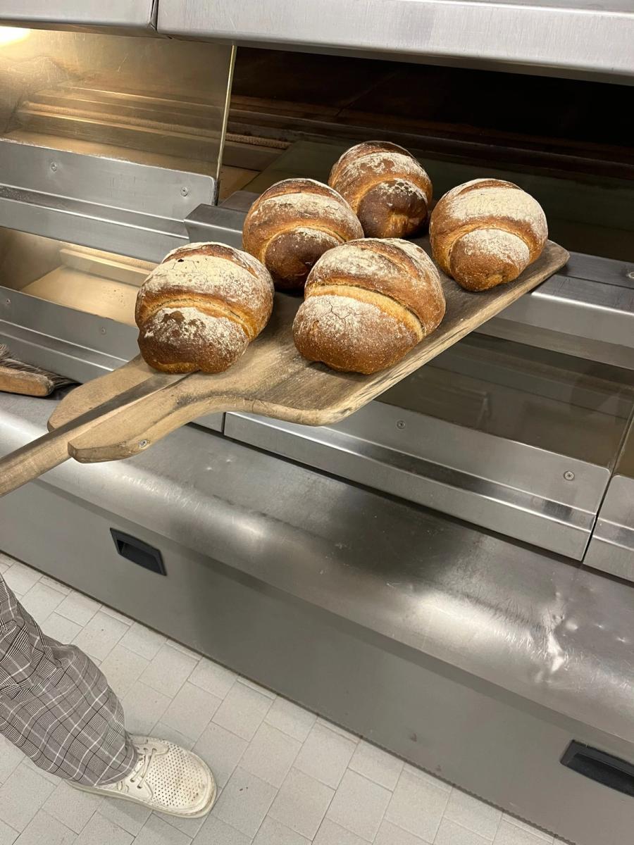 Bäcker zieht frische Brote aus dem Holzbackofen