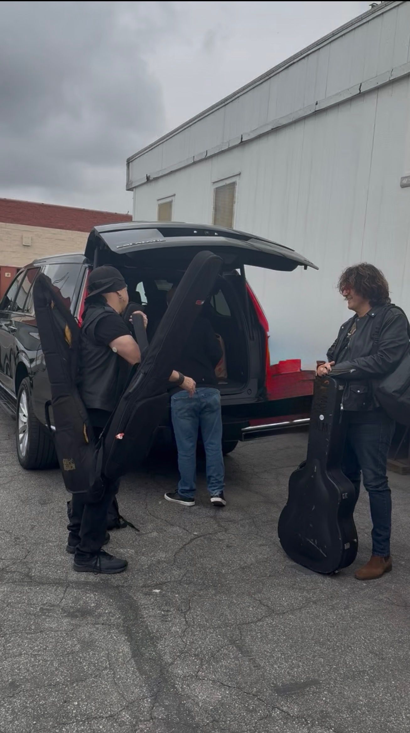 Musicians unloading guitar cases from an SUV outside The Kitchen recording studio in Los Angeles.