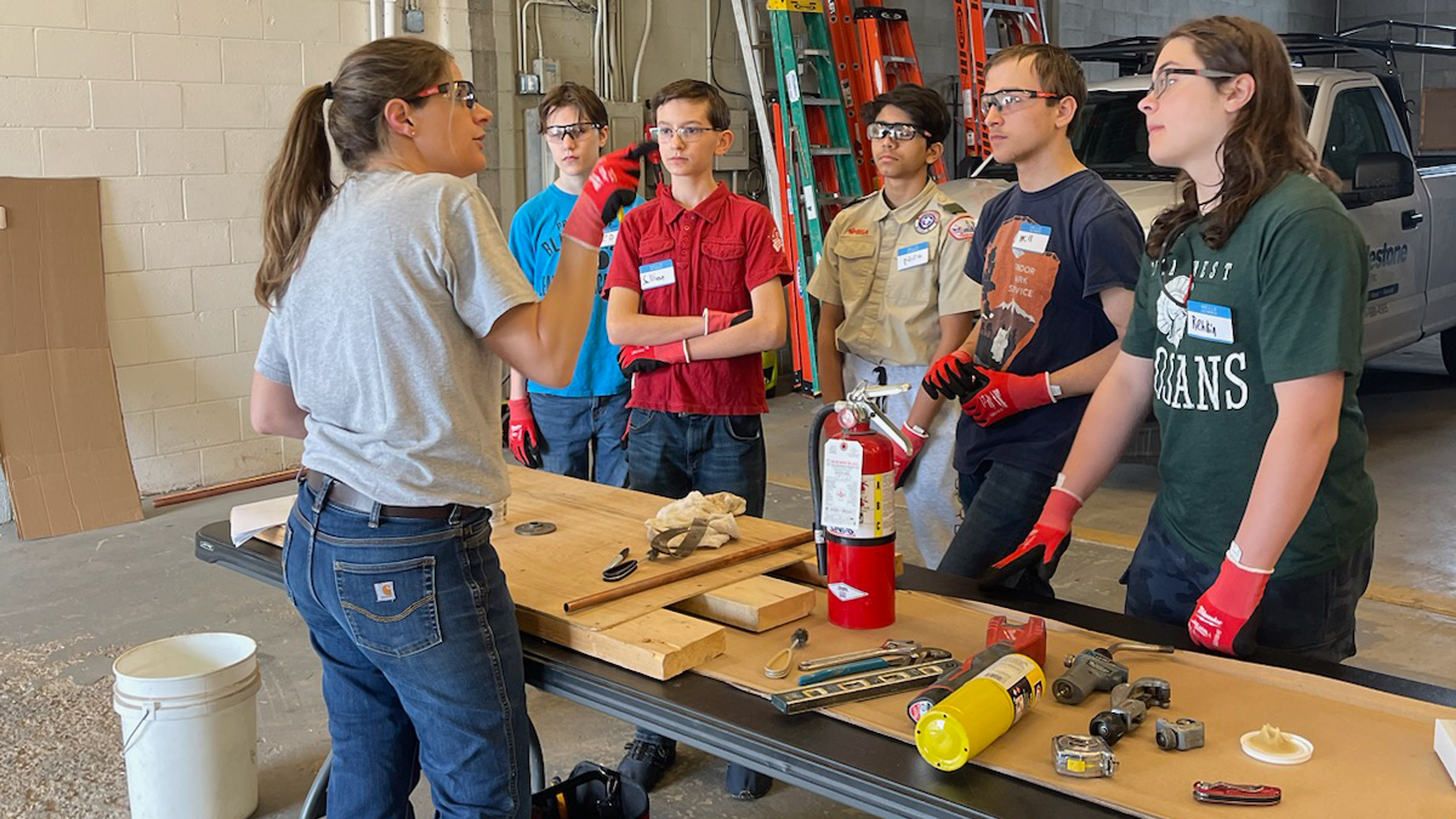 a female plumber teaches a plumbing course to high school students