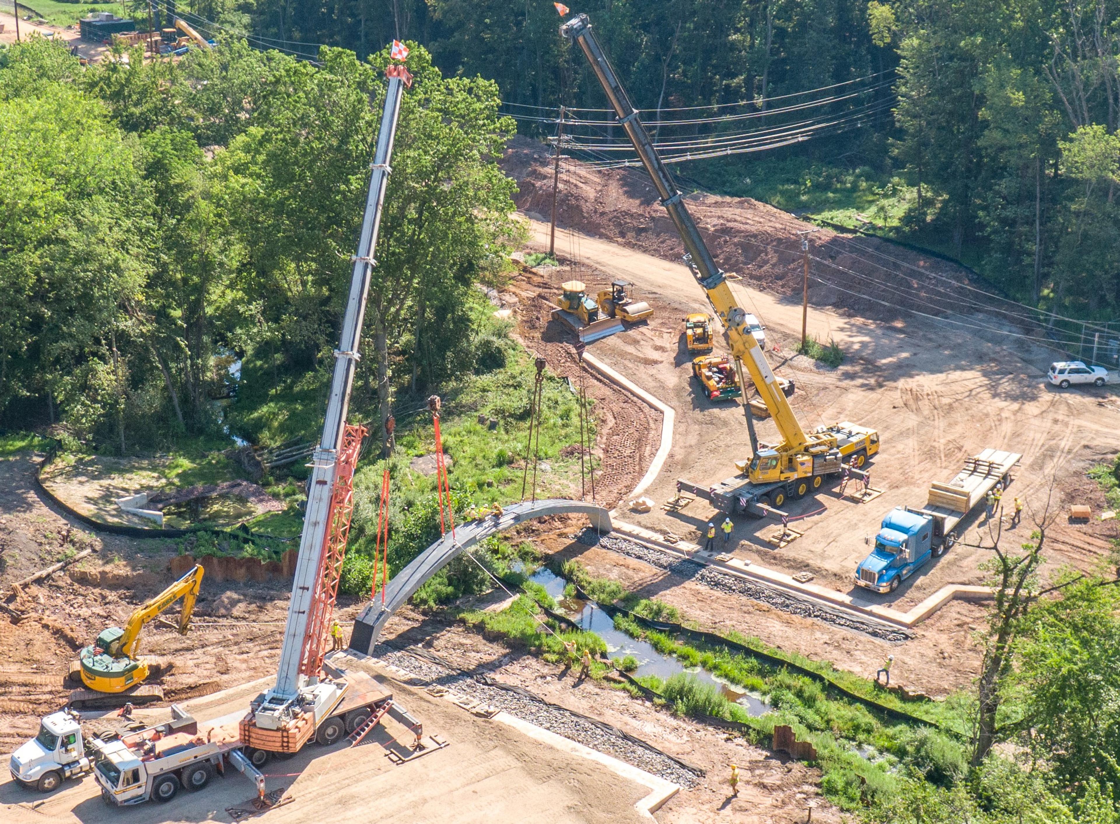 a pair of construction cranes erecting a bridge 