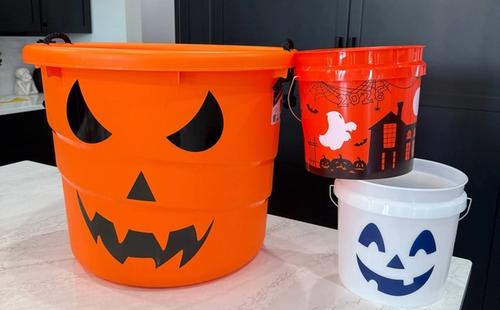 Halloween buckets from Lowes, Home Depot and Petco lined up on a shelf
