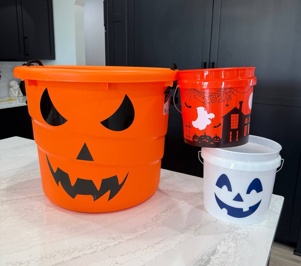 Halloween buckets from Lowes, Home Depot and Petco lined up on a shelf