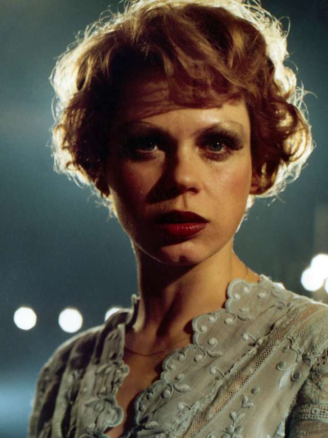 Solo Sunny / Renate Krössner / DEFA (DEFA14887) Photo of the actress Renate Krößner as Sunny in the film Solo Sunny (1980). The young woman is wearing a light-coloured embroidered blouse with a floral pattern, red lipstick and short hair. A string of lights can be seen blurred in the background.