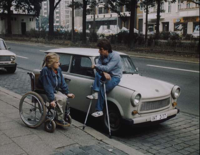 Ivo und Sabine, querschnittsgelähmt – DEFA/ PROGRESS Archive Sabine im Rollstuhl und Ivo mit Krücken vor einem Trabi