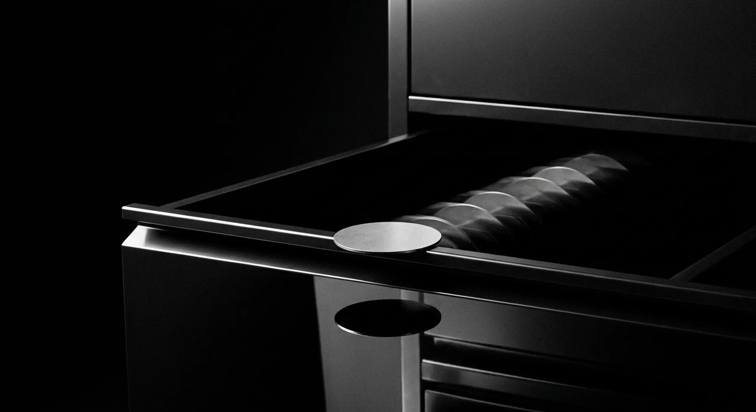 Modern black kitchen appliance with a circular silver knob blurred in motion across its surface.