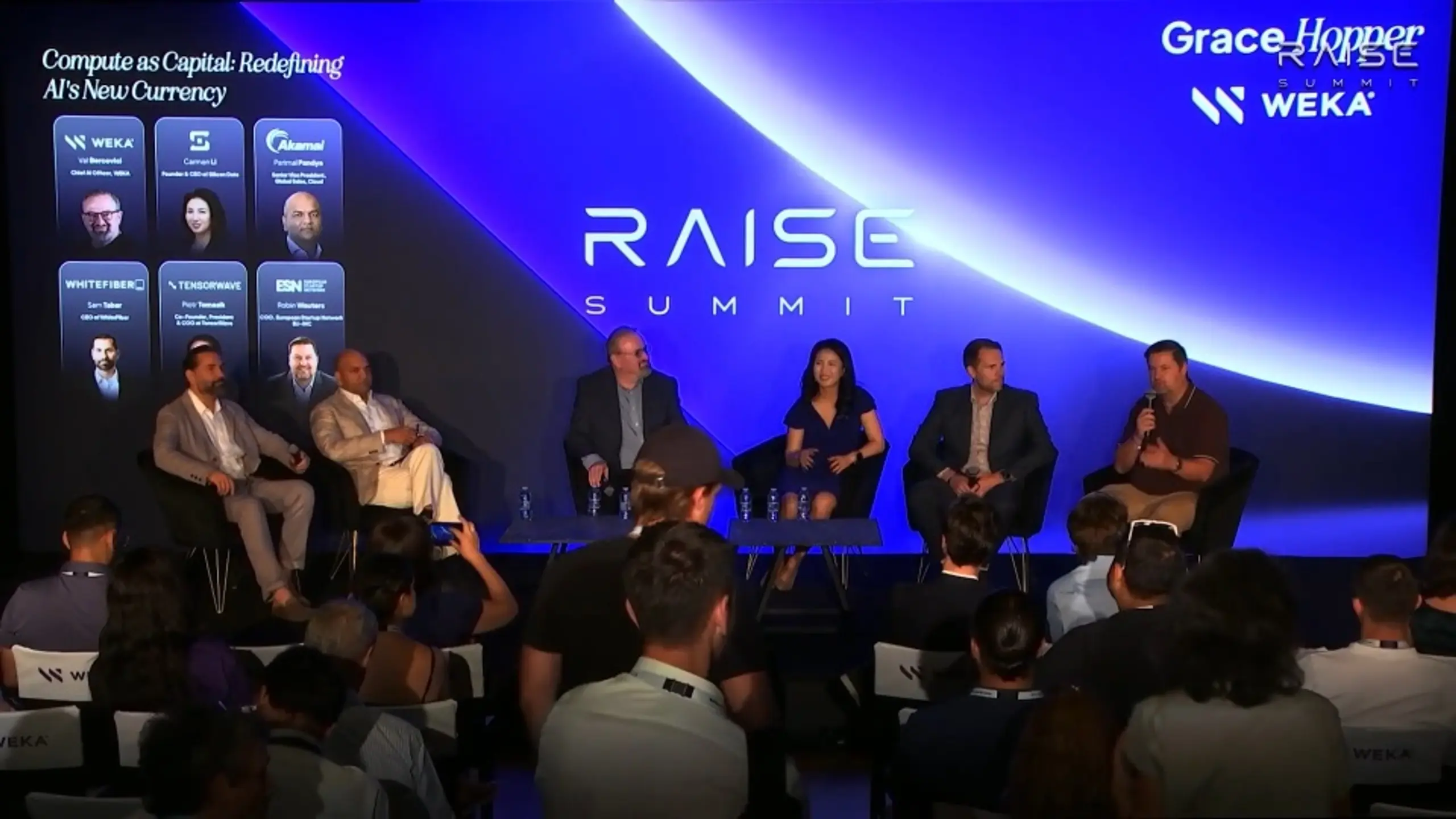 A panel discussion with five speakers on stage at the RAISE Summit, with an audience in the foreground.
