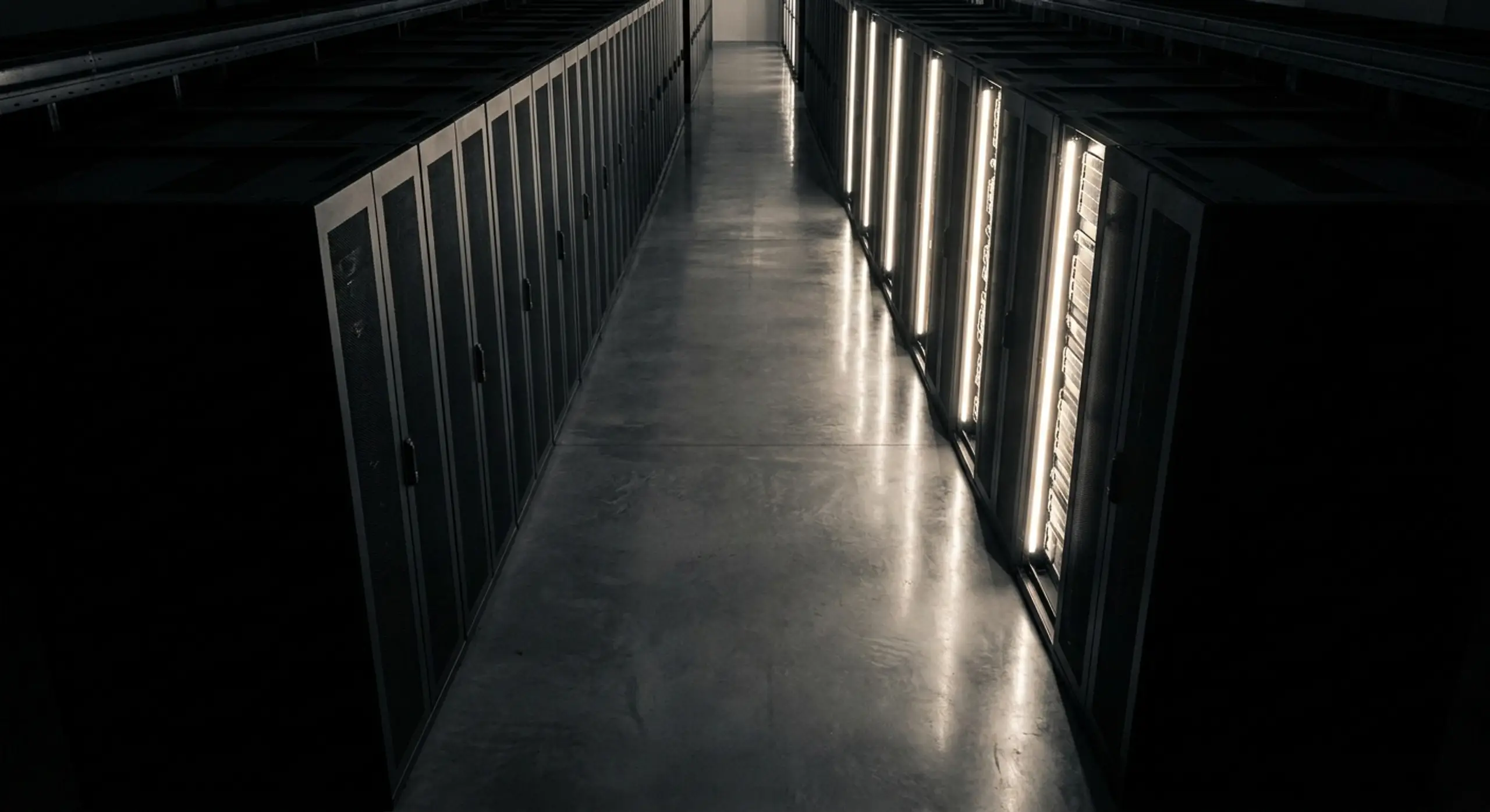 A long data center aisle with server racks, one side brightly lit.