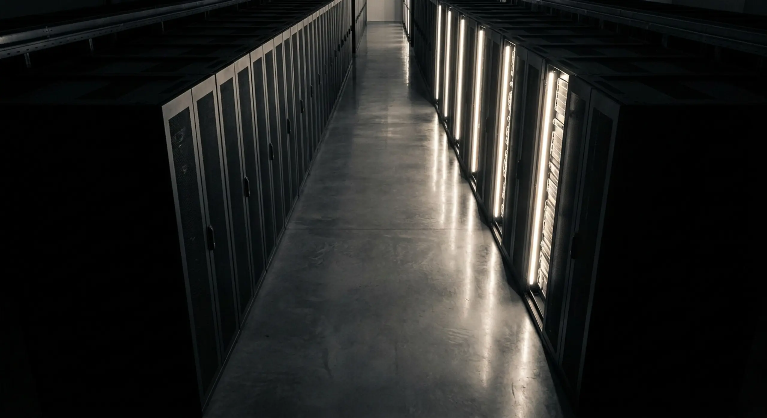 A long data center aisle with server racks, one side brightly lit.