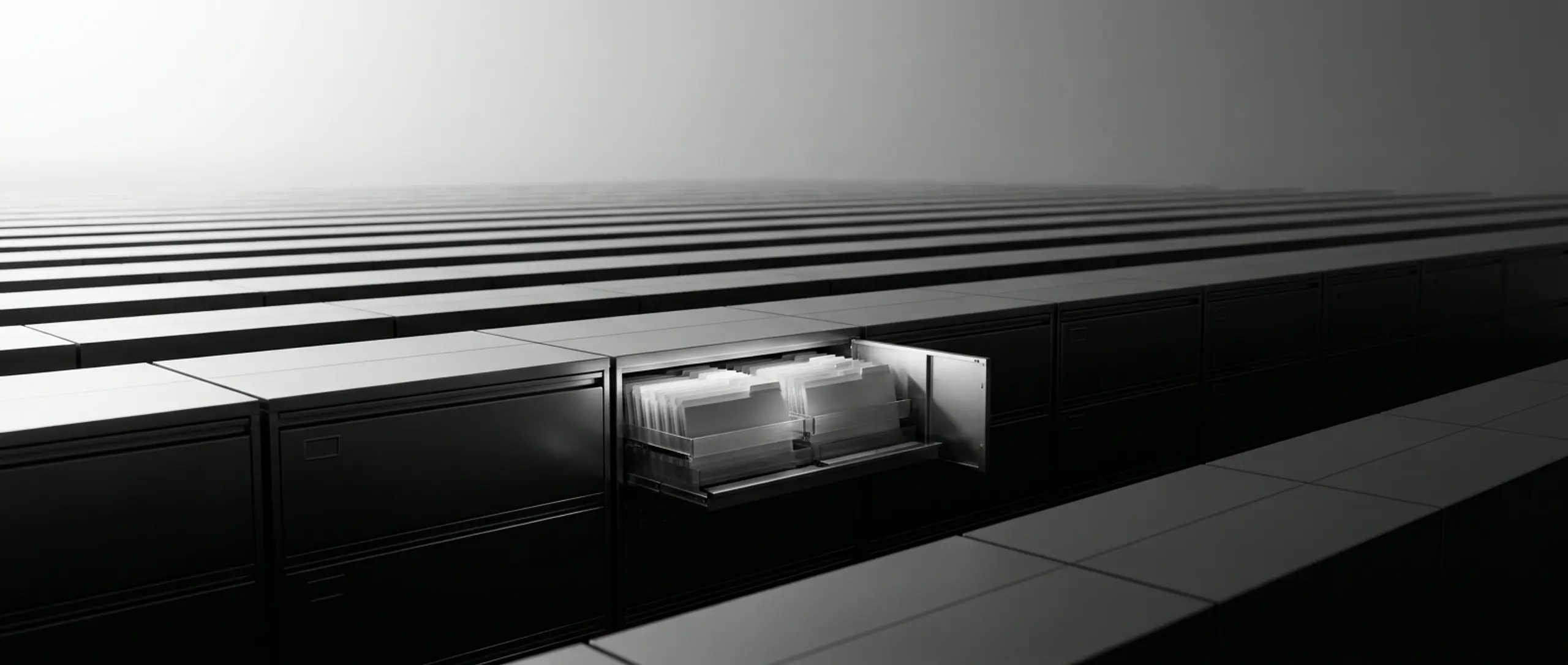 Vast black and white image of endless rows of filing cabinets, with one open drawer revealing files.