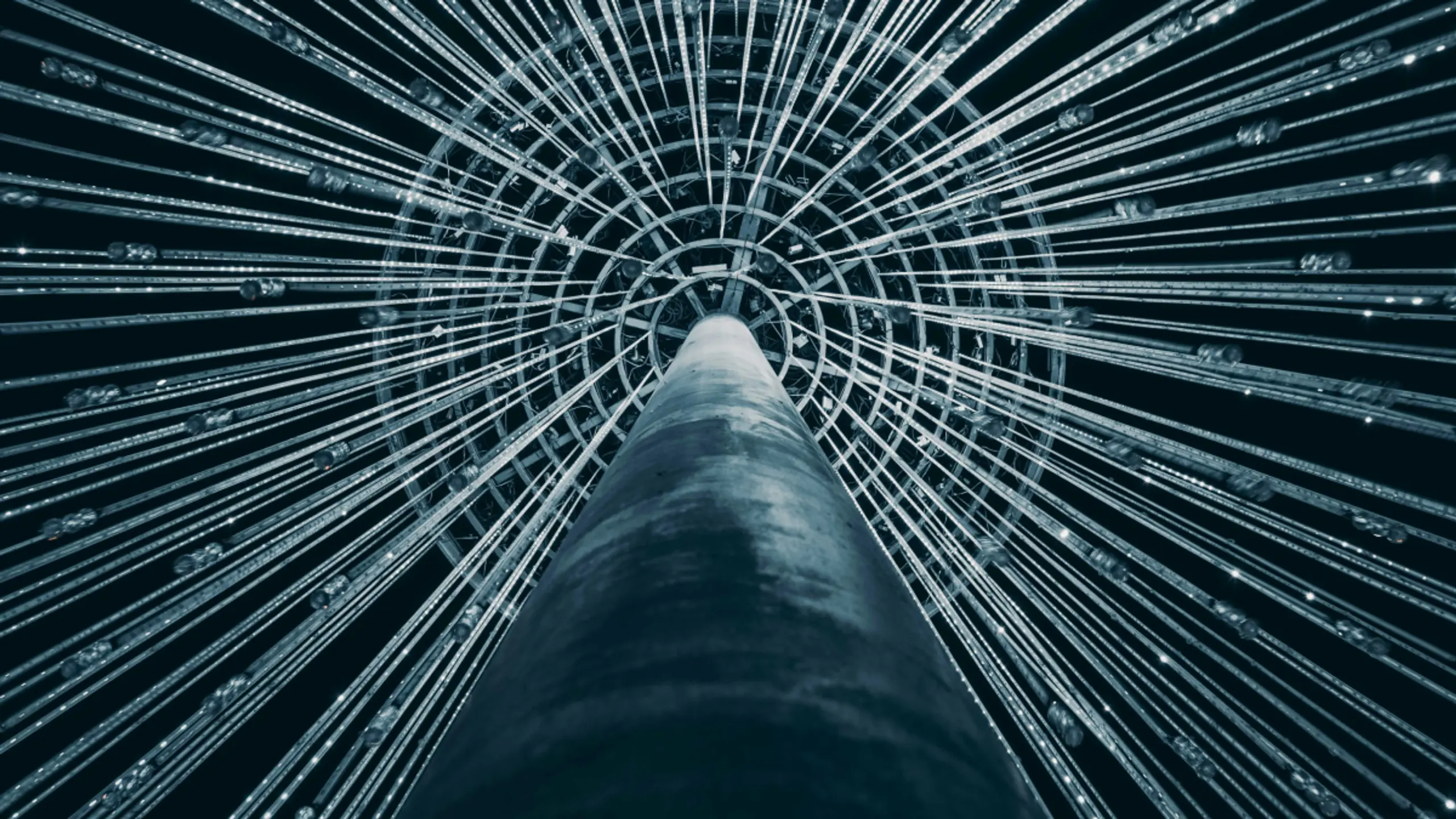 A dark pillar with illuminated lines radiating upwards to a circular grid.