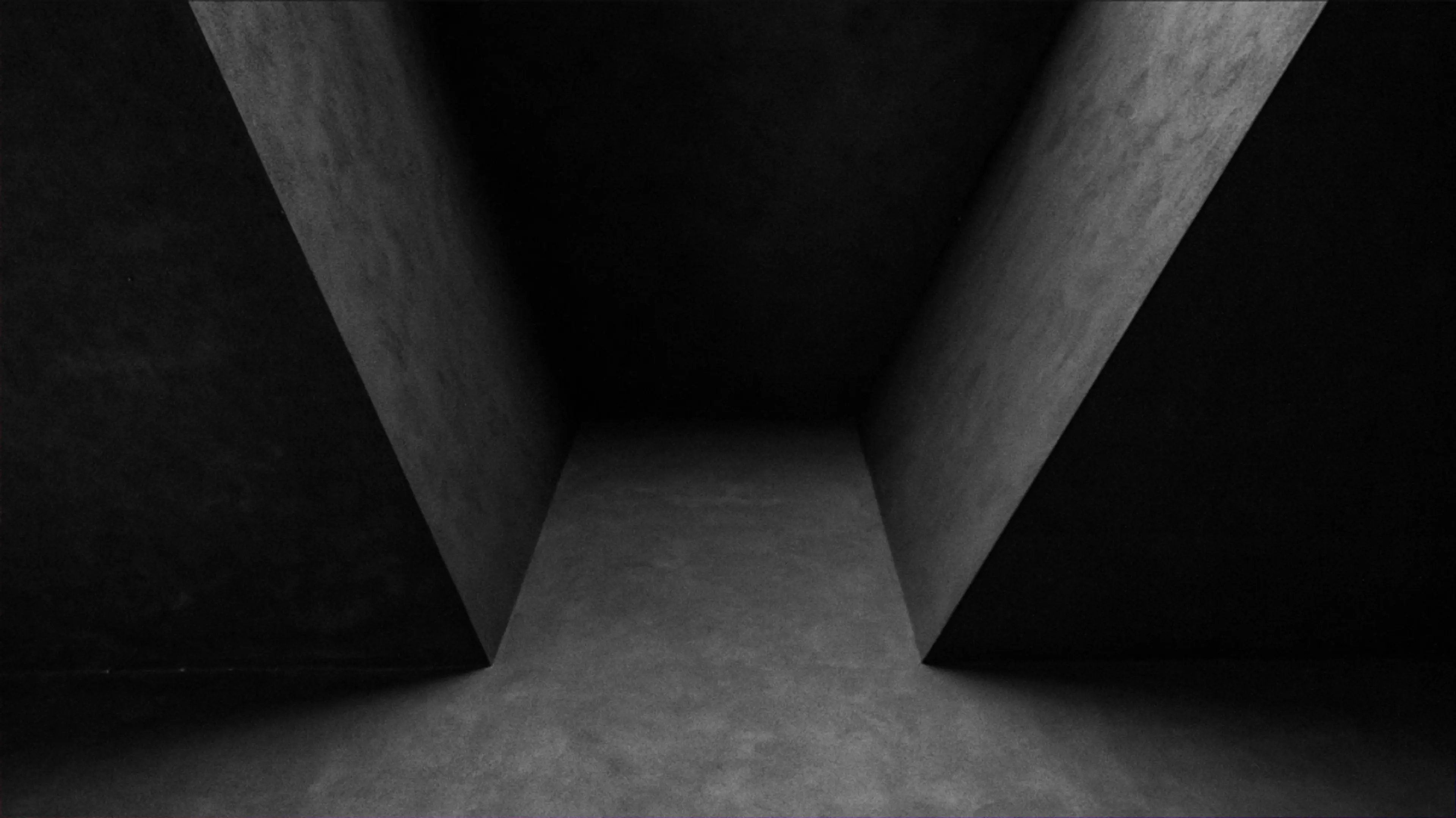 Abstract black and white concrete corridor with sharp angles and deep shadows.