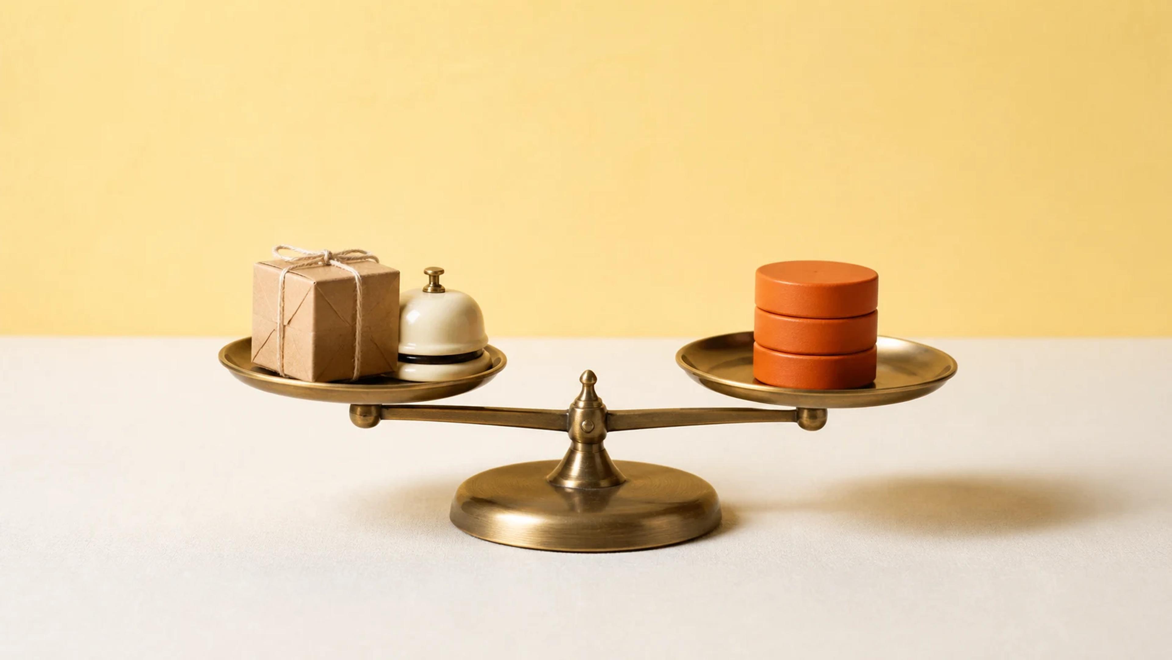 A balance scale weighing a parcel and service bell against unmarked value tokens