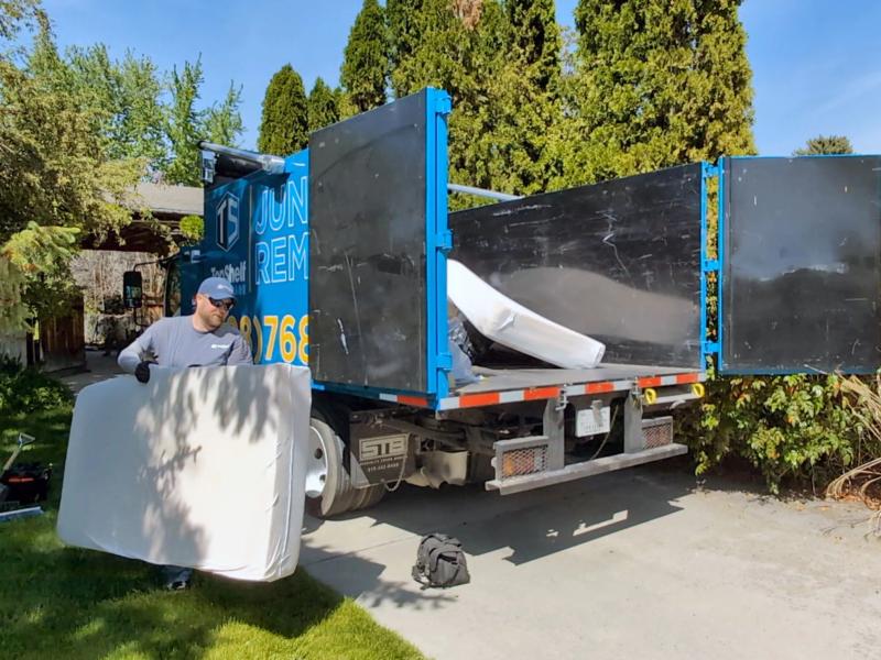 Top Shelf crew member loading a mattress into the branded junk removal truck at a residential driveway in Nampa Idaho