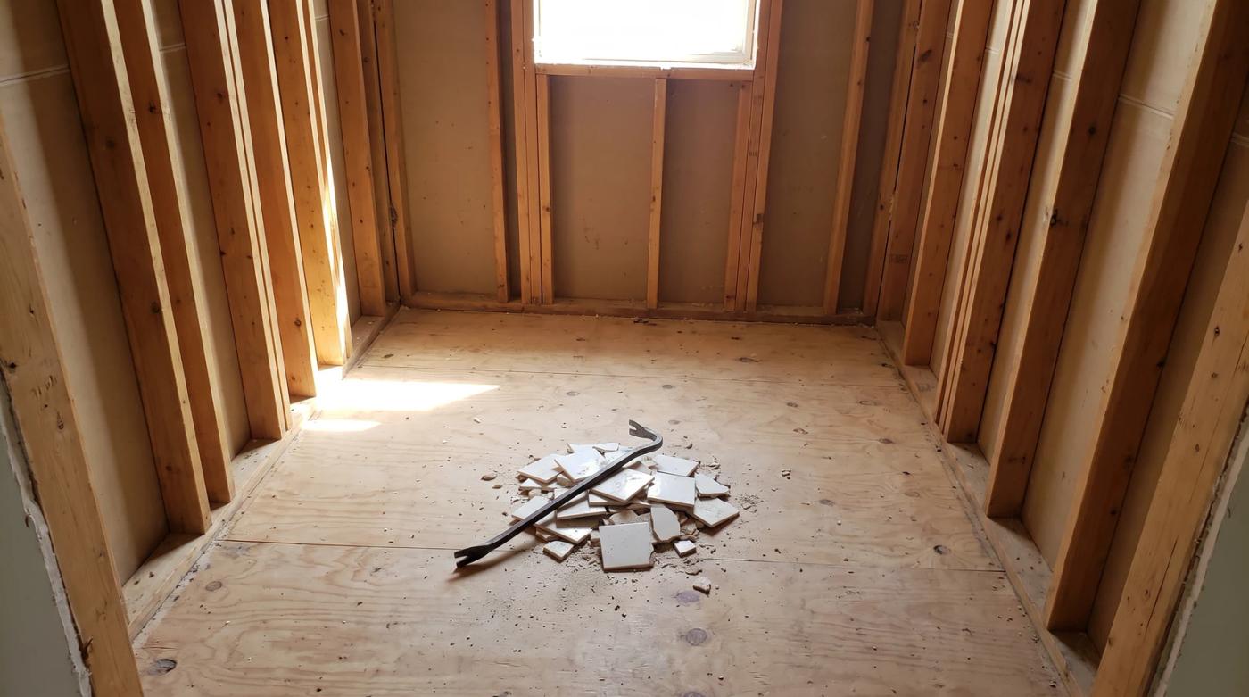 Bathroom stripped to the studs during an interior demolition in a Middleton, Idaho home, with broken tile piled on the bare subfloor