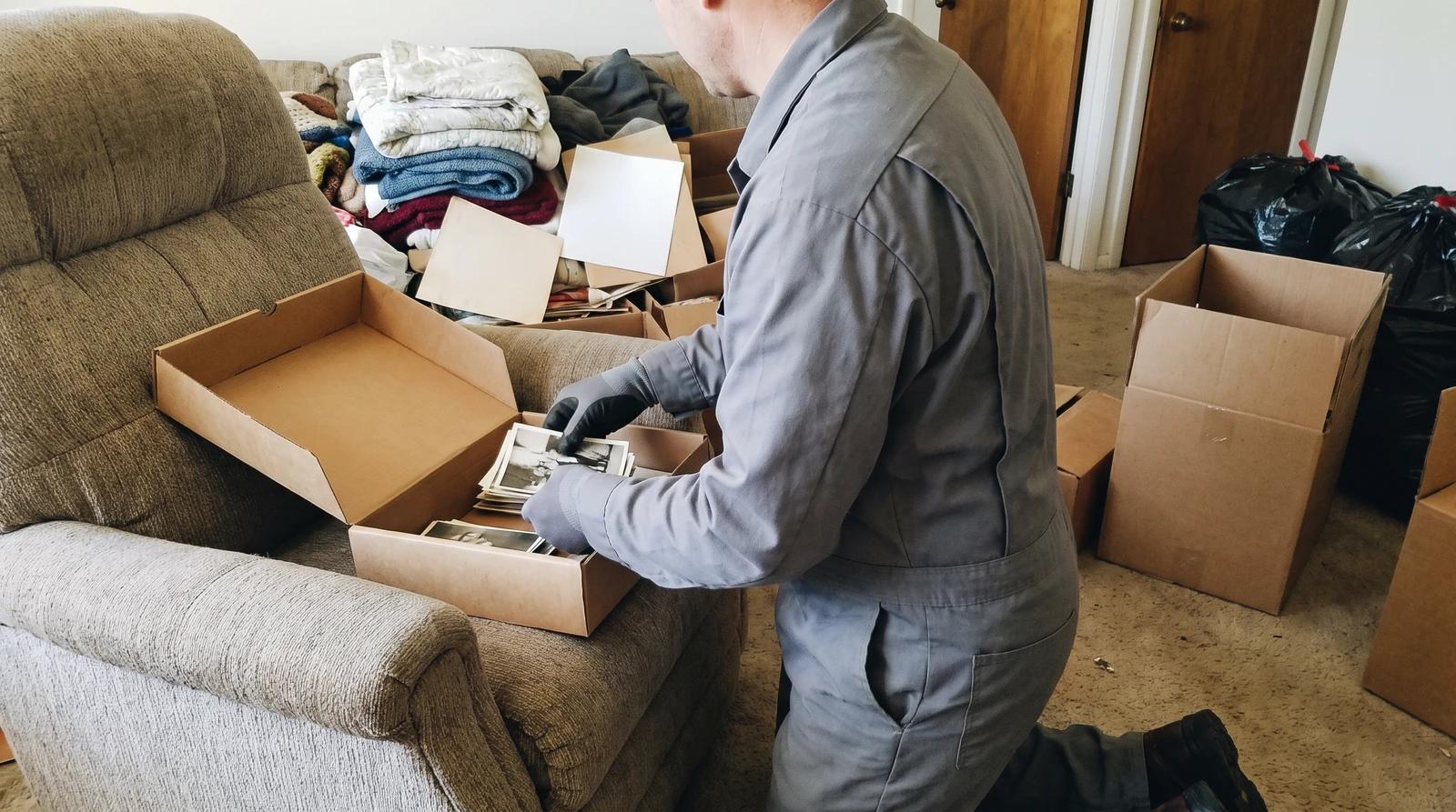 Hoarding cleanup crew member setting aside family photos and papers during an estate cleanout in a Garden City, Idaho home