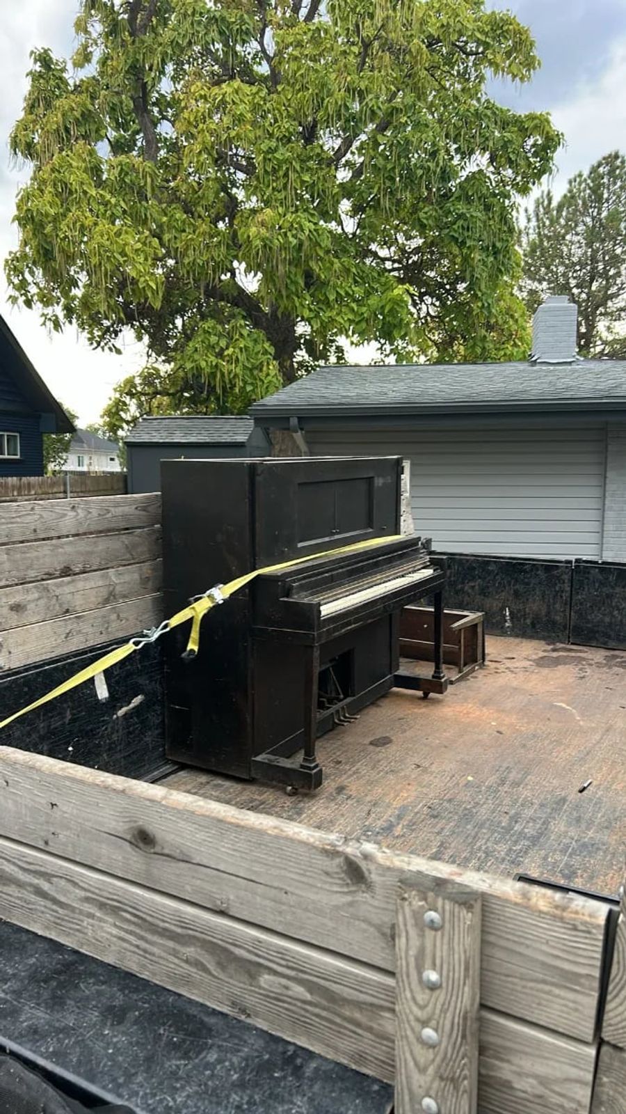 Upright piano strapped down in a junk removal trailer