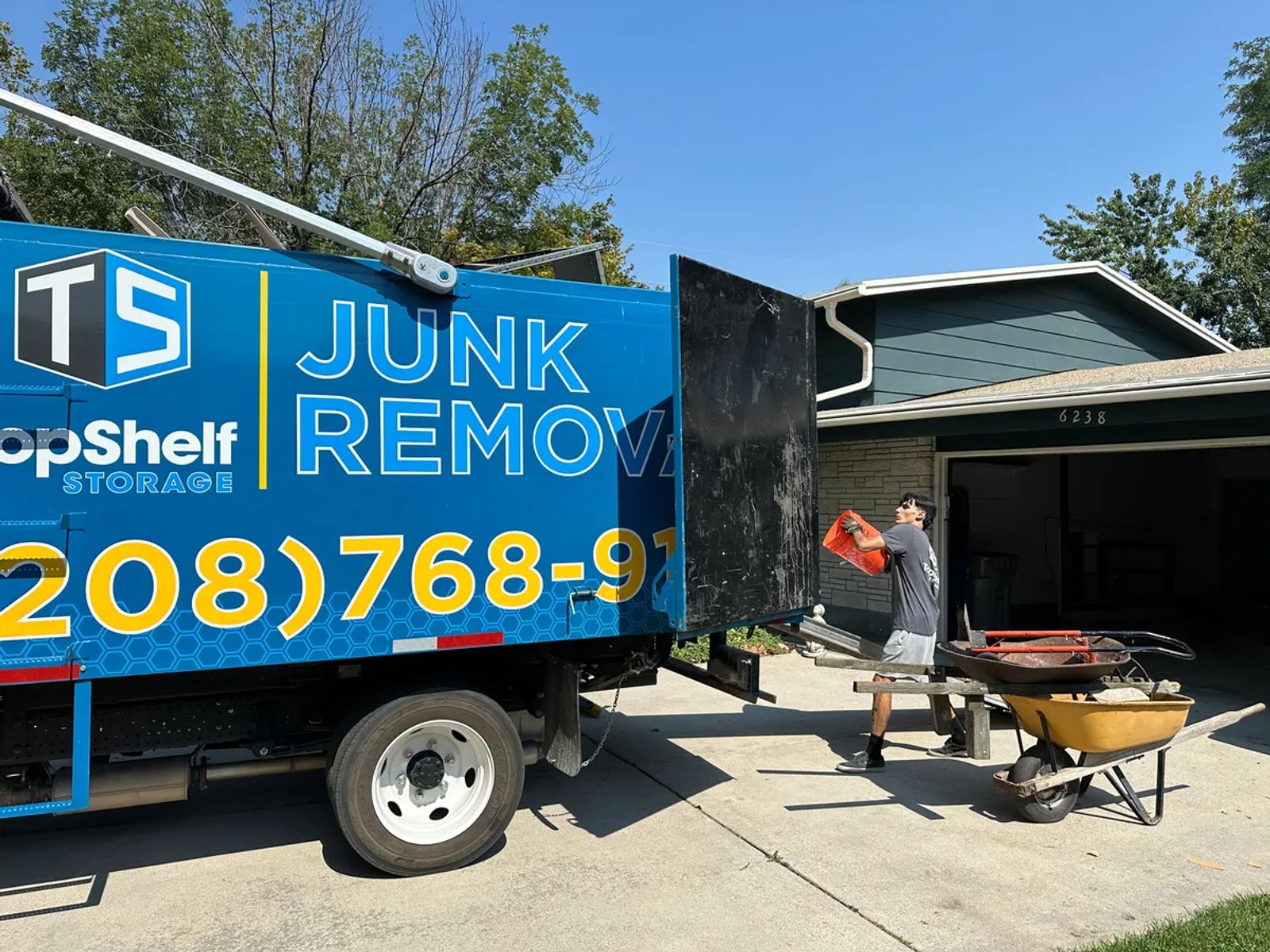 Top Shelf crew loading household junk into the branded truck from a driveway in Boise Idaho