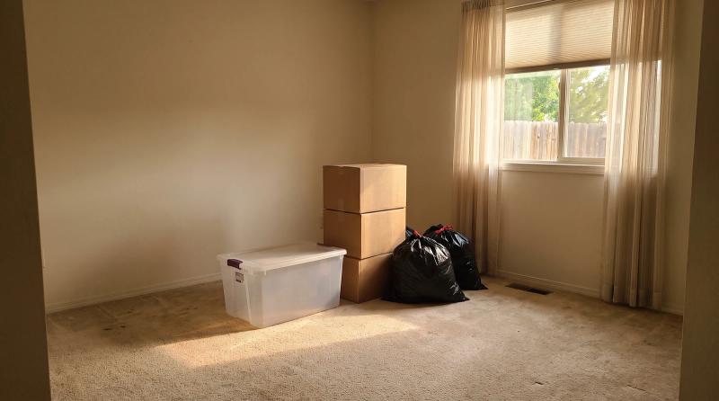 Sorted boxes, a storage tote and bagged items in a cleared-out bedroom during an empty nest cleanout in Eagle, Idaho