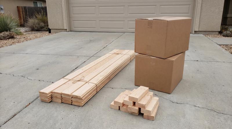 Leftover building materials sorted into neat stacks of tile boxes, trim boards, and scrap lumber on a driveway outside a home in Kuna, Idaho