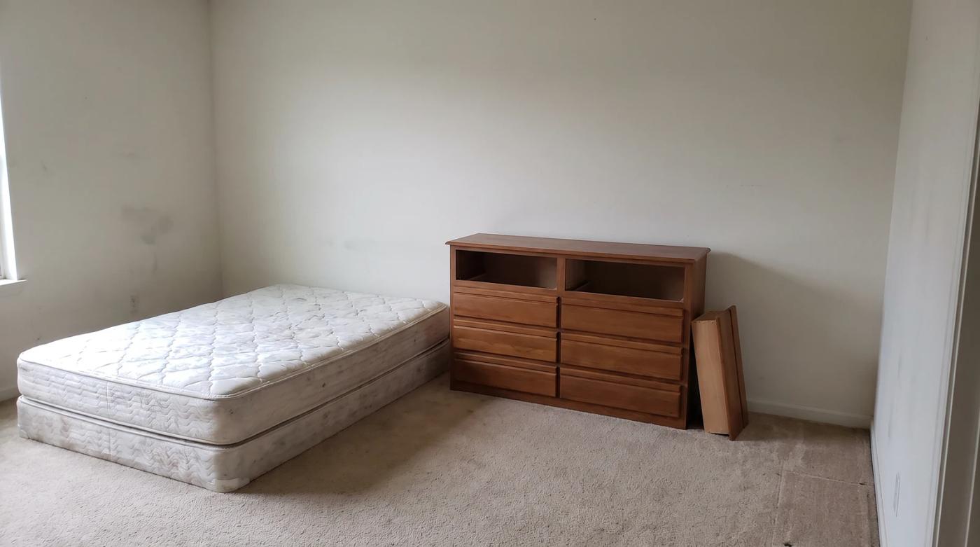 Bare mattress and a dresser missing two drawers left behind in an empty rental bedroom in Meridian, Idaho