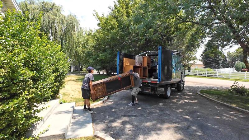 Top Shelf crew loading a dresser into the junk removal truck in Meridian Idaho