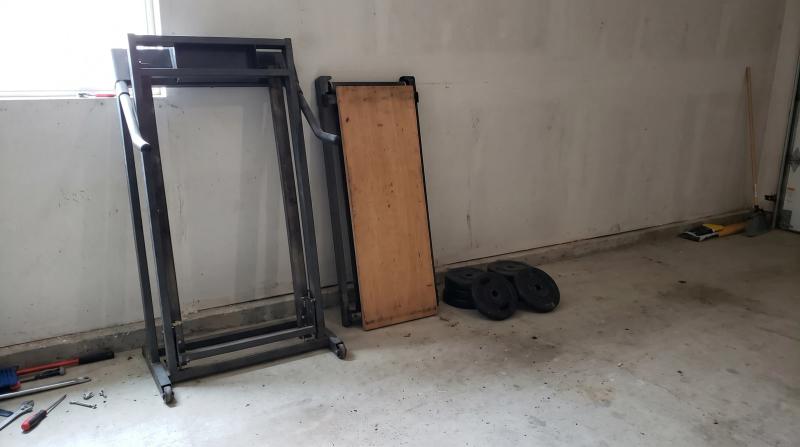 Disassembled treadmill frame leaning against a garage wall next to stacked weight plates during an exercise equipment removal job in Eagle, Idaho