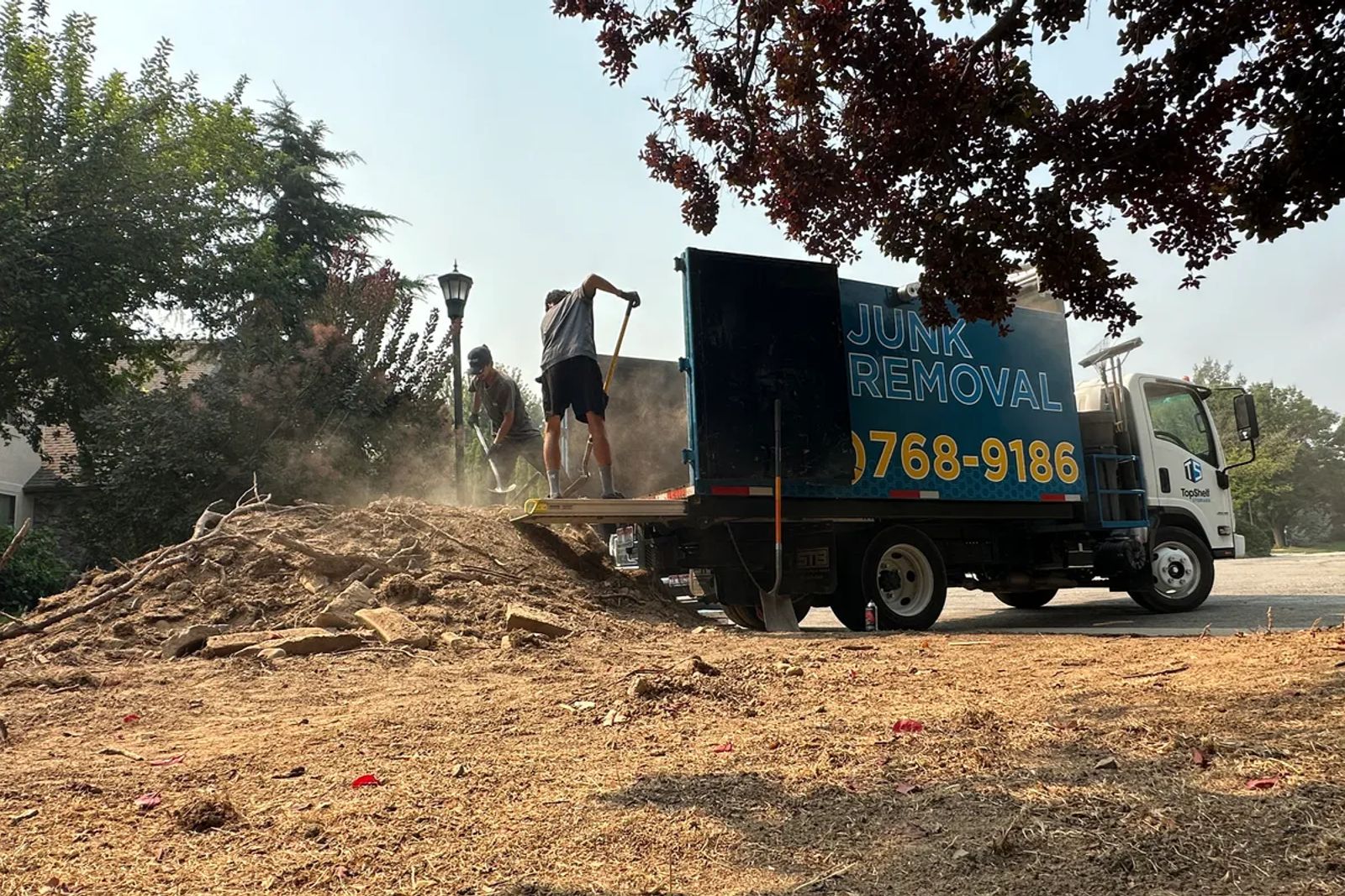 Top Shelf junk removal crew loading dirt and debris into truck during a job in Caldwell Idaho