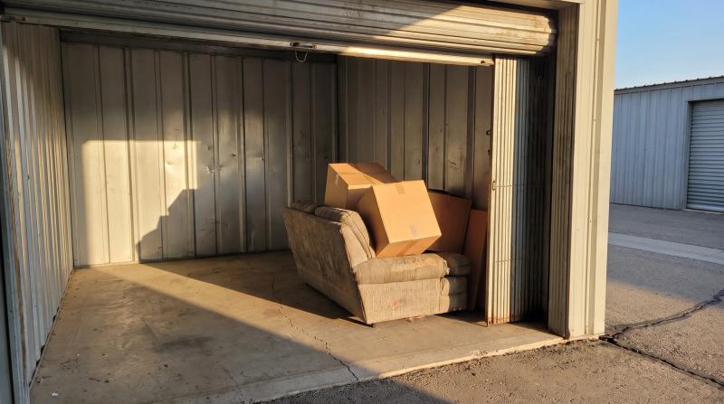 Open storage unit filled with stacked boxes and an old armchair during a cleanout in Nampa, Idaho