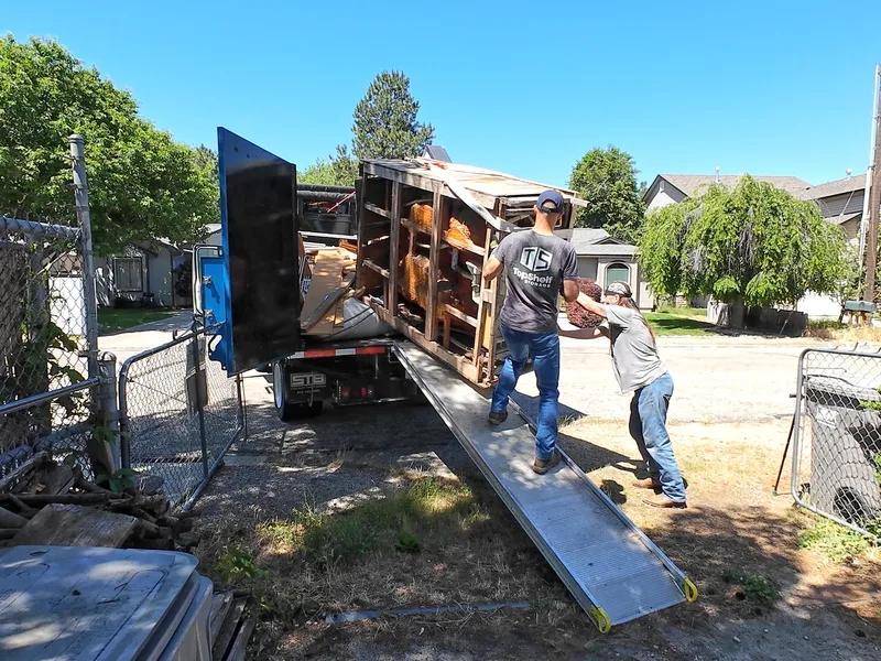 Top Shelf crew hauling dismantled hot tub debris up the truck ramp in Caldwell Idaho