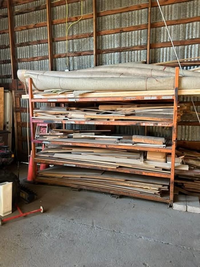 Metal shelving loaded with scrap lumber and old materials inside a shop building before a cleanout