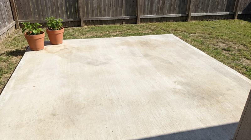 Empty concrete patio pad in a Boise, Idaho backyard after hot tub removal, with potted plants and a wooden fence