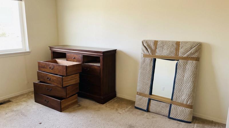 Old wood dresser with drawers removed and a wrapped mirror ready for bedroom furniture removal in a home in Star, Idaho