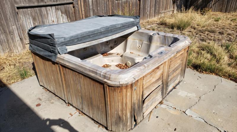 Weathered old hot tub with a faded cover waiting for disposal in a backyard in Nampa, Idaho