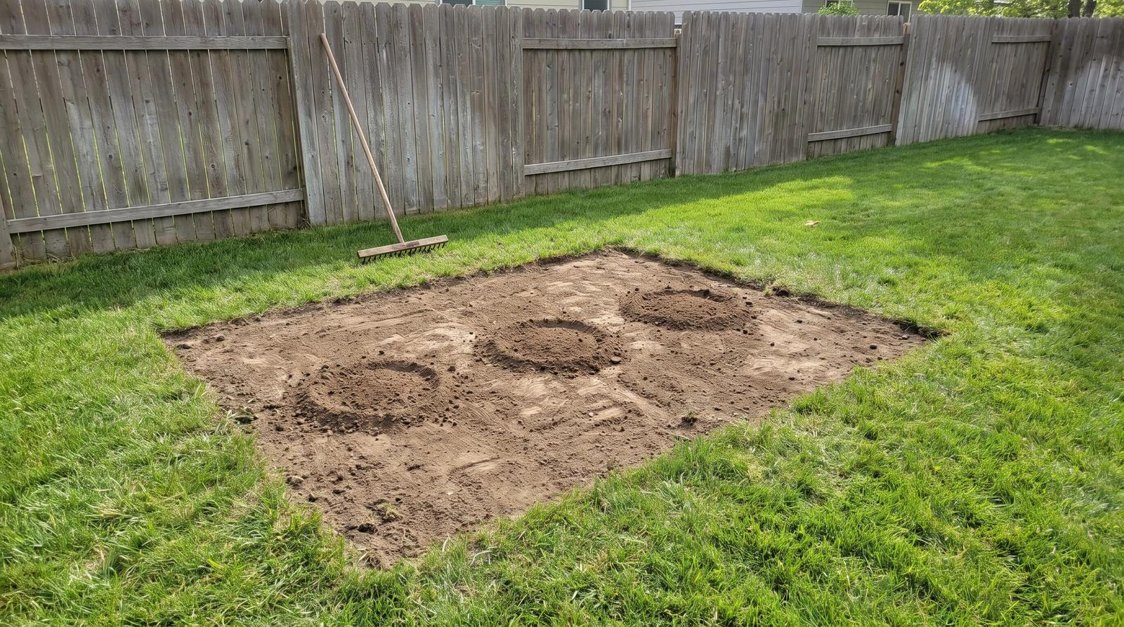 Bare patch of ground and a rake in a Kuna, Idaho backyard after an old playhouse was removed