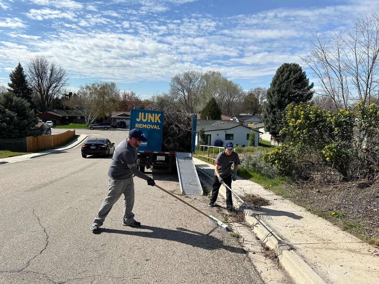 Top Shelf crew raking up tree branches during a yard debris removal job