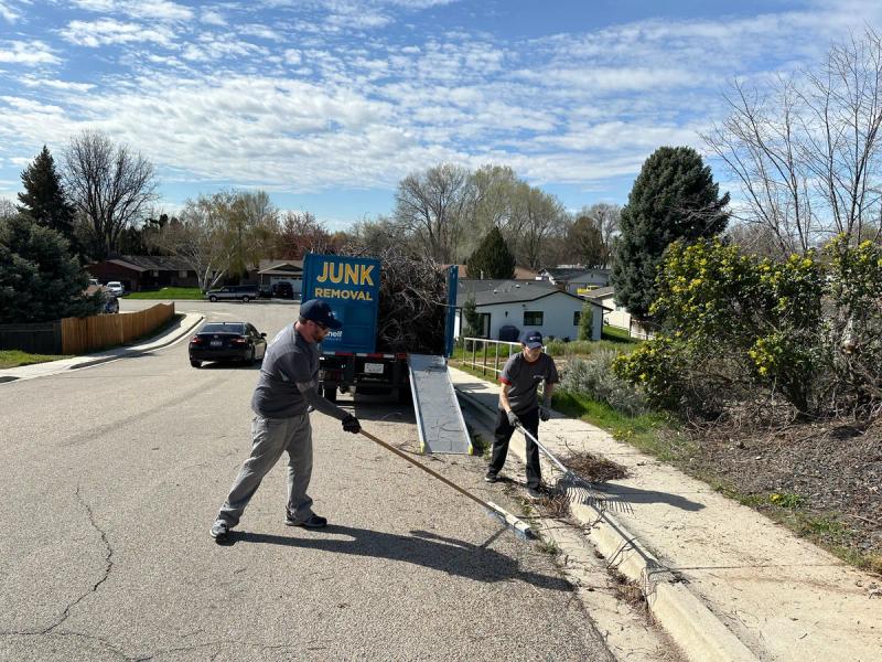 Top Shelf crew raking up tree branches during a yard debris removal job