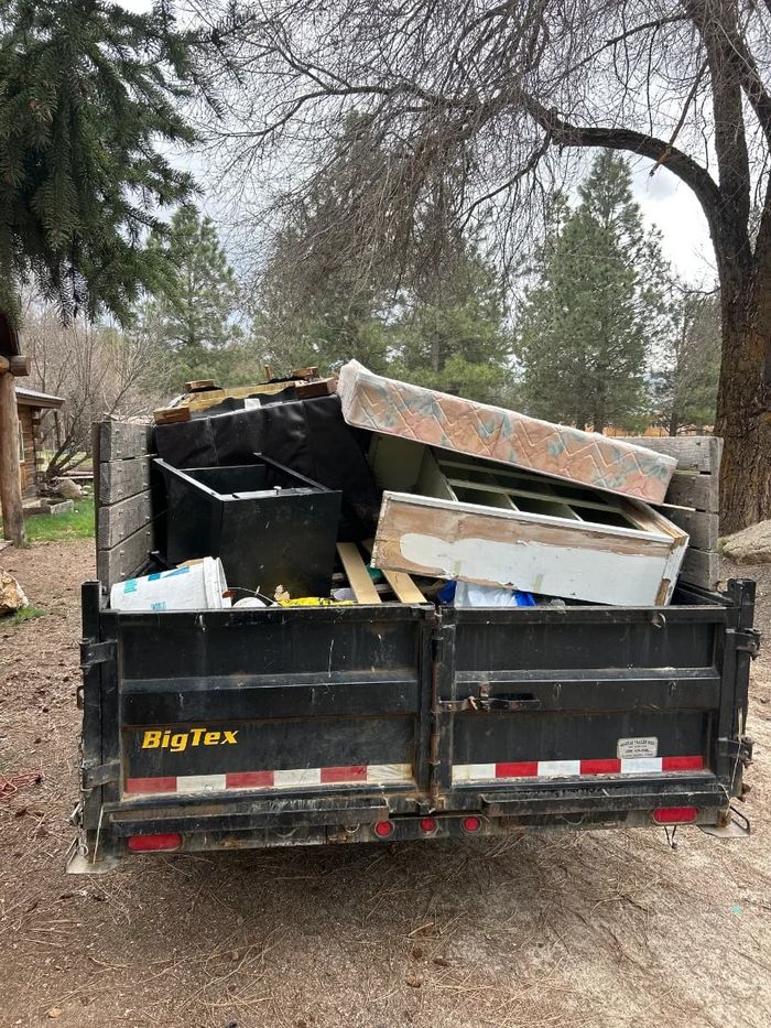 Dump trailer loaded with a mattress, boxes and household junk
