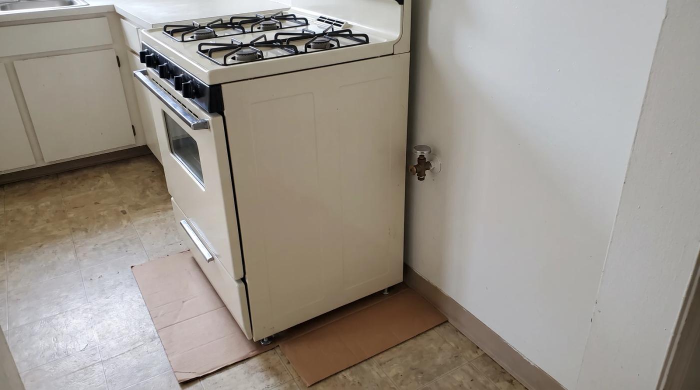 Old white gas range pulled away from the kitchen wall with the gas line capped, ready for appliance removal in Boise, Idaho