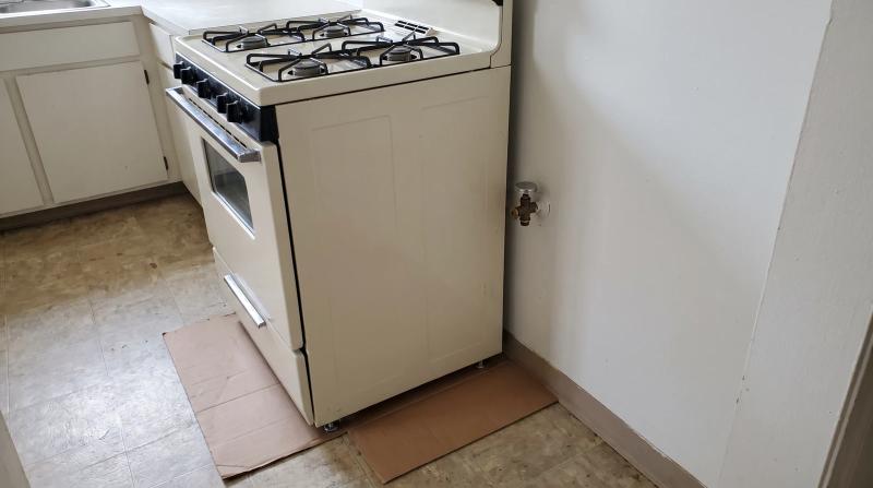 Old white gas range pulled away from the kitchen wall with the gas line capped, ready for appliance removal in Boise, Idaho