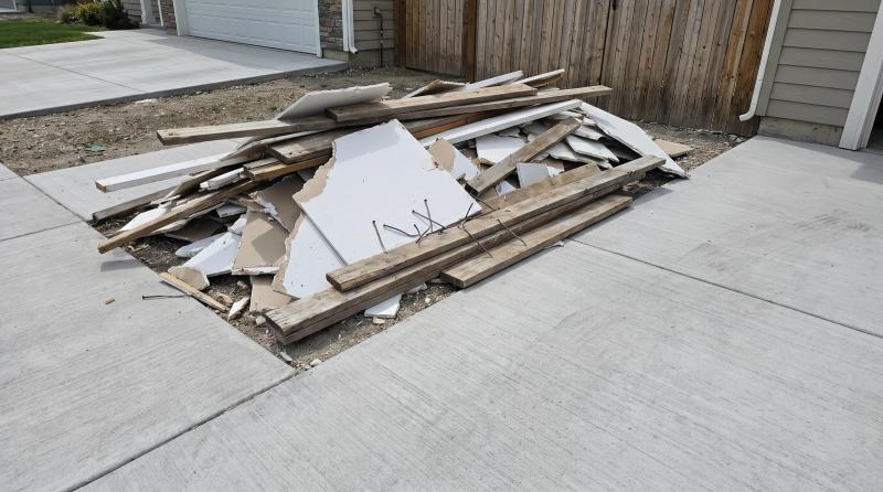 Pile of drywall and lumber construction debris ready for cleanup on a driveway in Nampa, Idaho