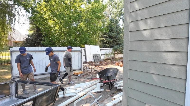Top Shelf crew cleaning up construction debris with windows trim and rocks in a residential backyard in Star Idaho