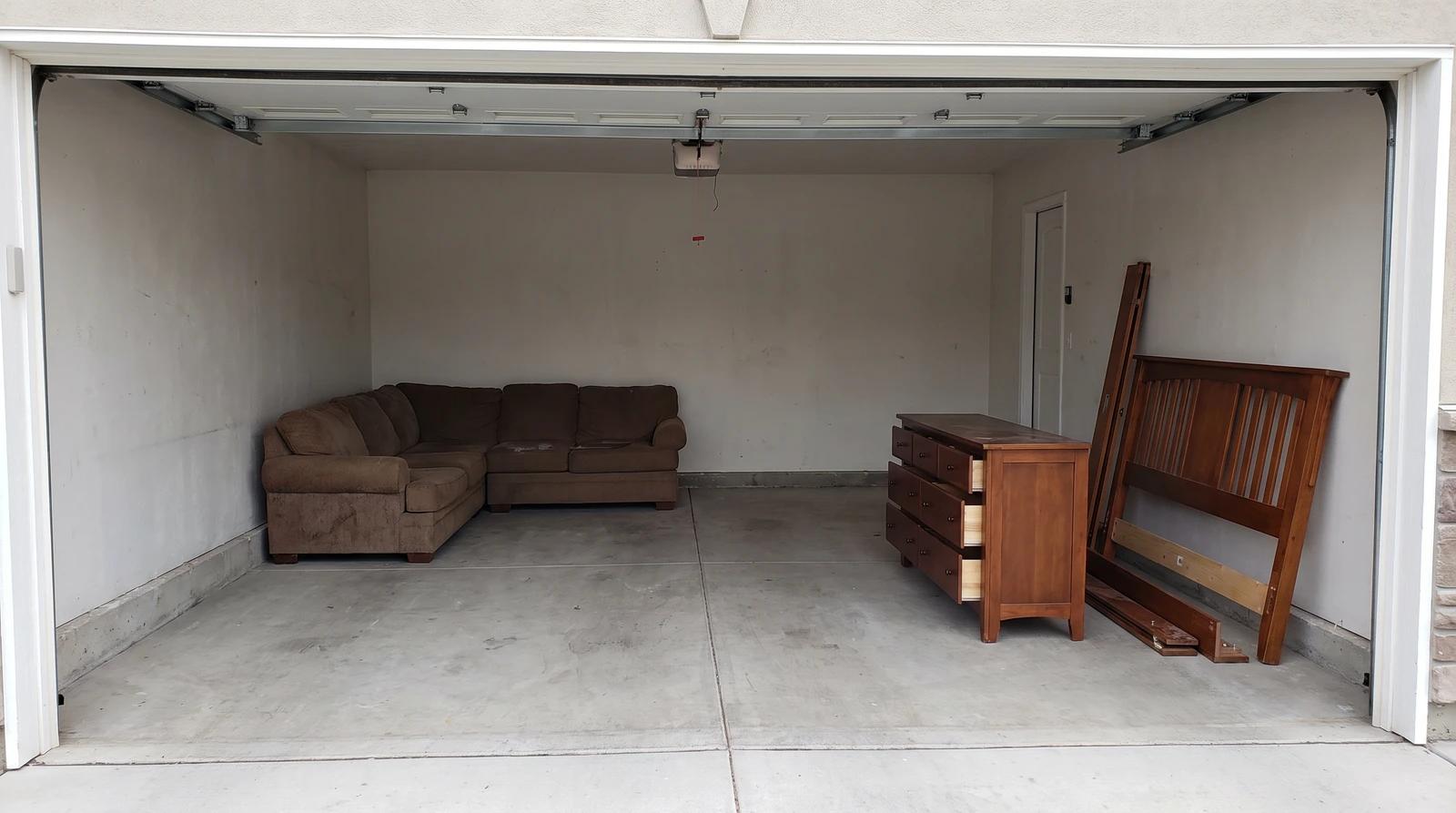 Old sectional sofa, wooden dresser and a broken-down bed frame gathered in a Garden City, Idaho garage, ready for junk removal