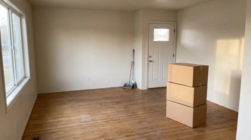 Cleared rental living room in Garden City, Idaho after a landlord hoarding cleanup, with sealed boxes stacked by the front door