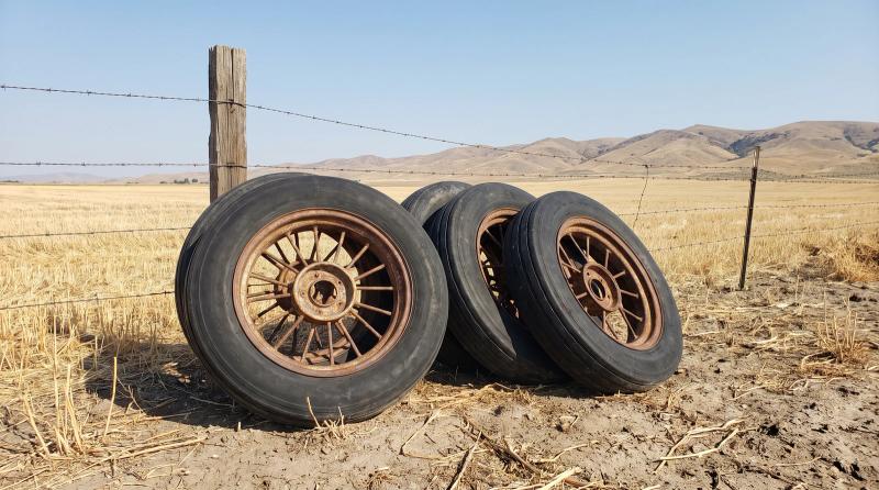 Old cracked center pivot irrigation tires on rusty wheels stacked at the edge of a harvested field near Nampa, Idaho