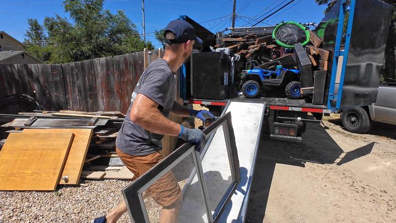 Top Shelf crew member loading wood scraps and window screen frames into the truck after a new construction cleanup in Boise Idaho