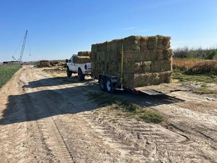 A trailer of hay bales being delivered to a farm property