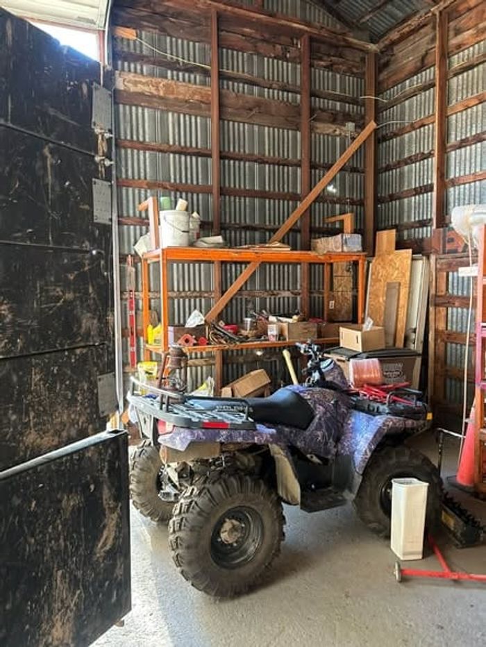 An ATV parked among shelves of clutter inside a barn before a cleanout