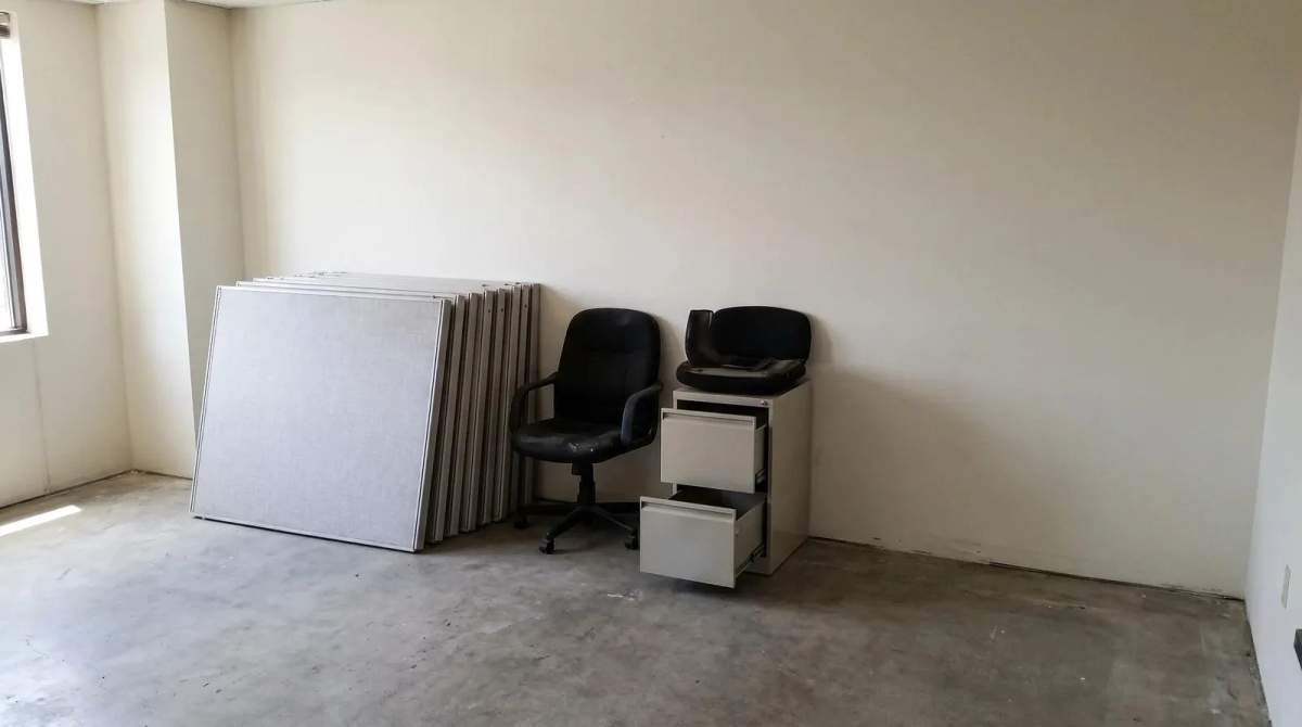 Disassembled cubicle panels, office chairs and an empty filing cabinet left behind in a vacated office suite during a commercial cleanout in Meridian, Idaho.
