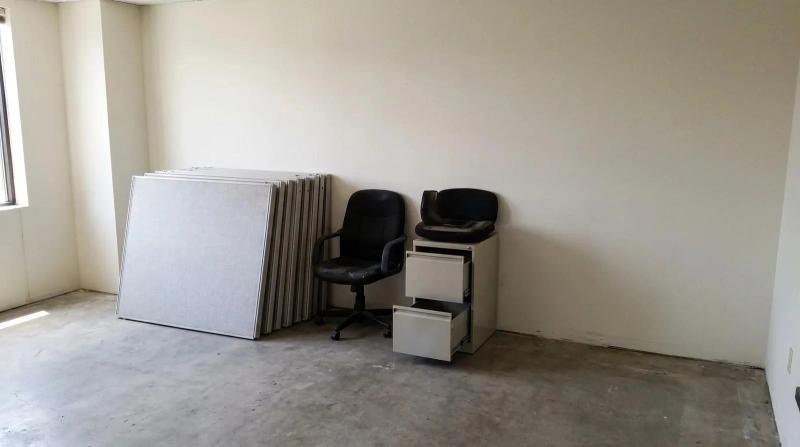 Disassembled cubicle panels, office chairs and an empty filing cabinet left behind in a vacated office suite during a commercial cleanout in Meridian, Idaho.